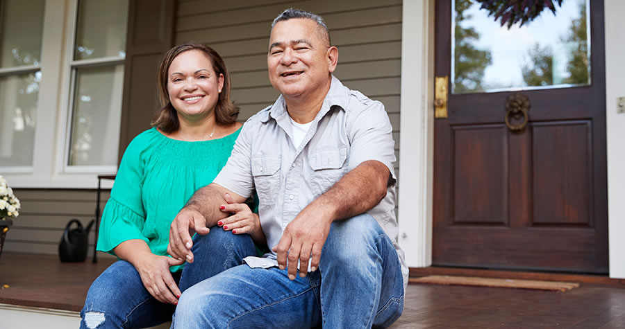 Couple sitting on the steps in front of their home