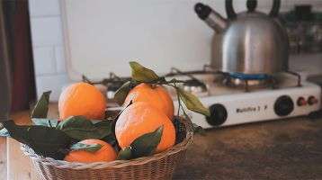 Basket of oranges and a teapot warming on the stove