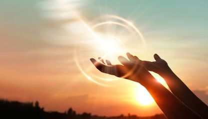 Hands raised in praise in the light of dawn.