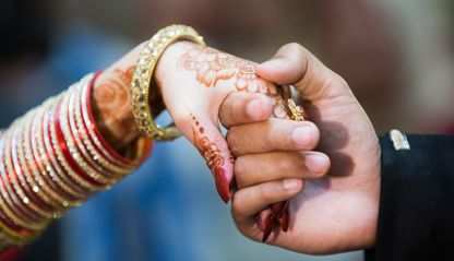 Bride and groom hold hands during Pakistani wedding
