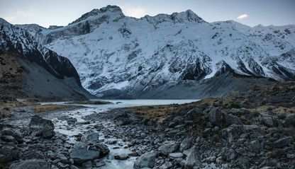Snow-covered mountains with stream of glacial runoff.