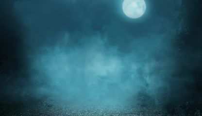 The moon peeks through a dark cloudy night