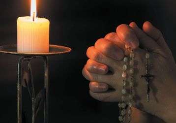 Praying the rosary in front of a lit candle