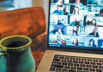 A desktop with an open laptop computer and coffee cup